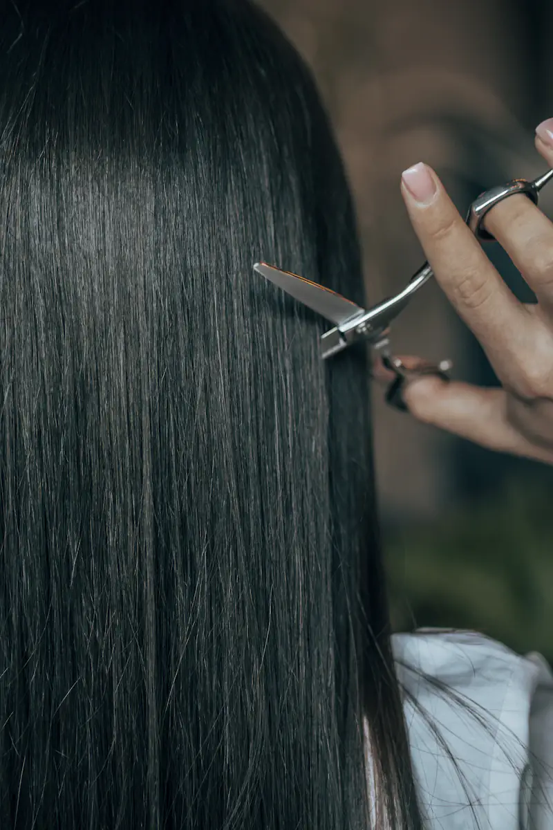 Tesoura cortando uma mecha de cabelo escuro e liso